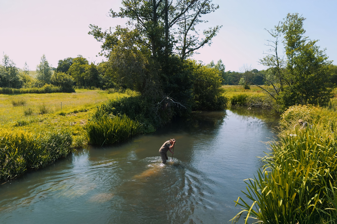 Image of a man in the river carrying out a survey